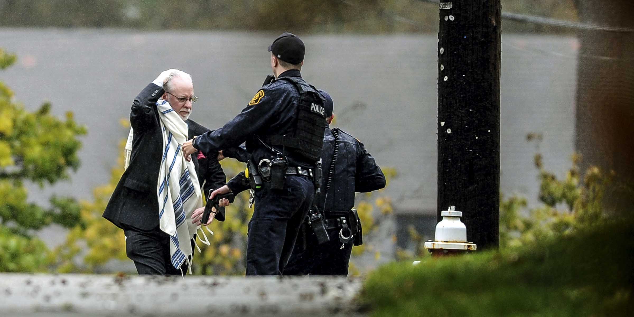 A man holds his head as he is escorted out of the Tree of Life Congregation by police following a shooting at the Pittsburgh synagogue Saturday, Oct. 27, 2018. (Alexandra Wimley/Pittsburgh Post-Gazette via AP)